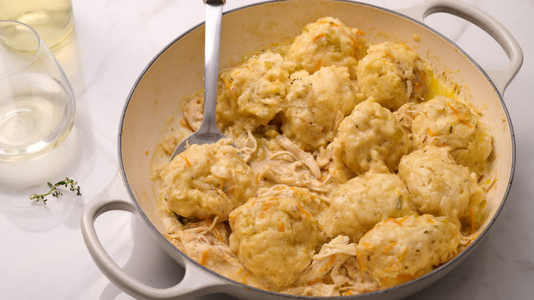 Chicken and dumplings being spooned out of casserole pan