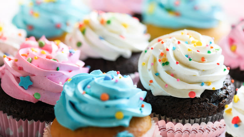 A variety of cupcakes with different colored buttercream icing on top