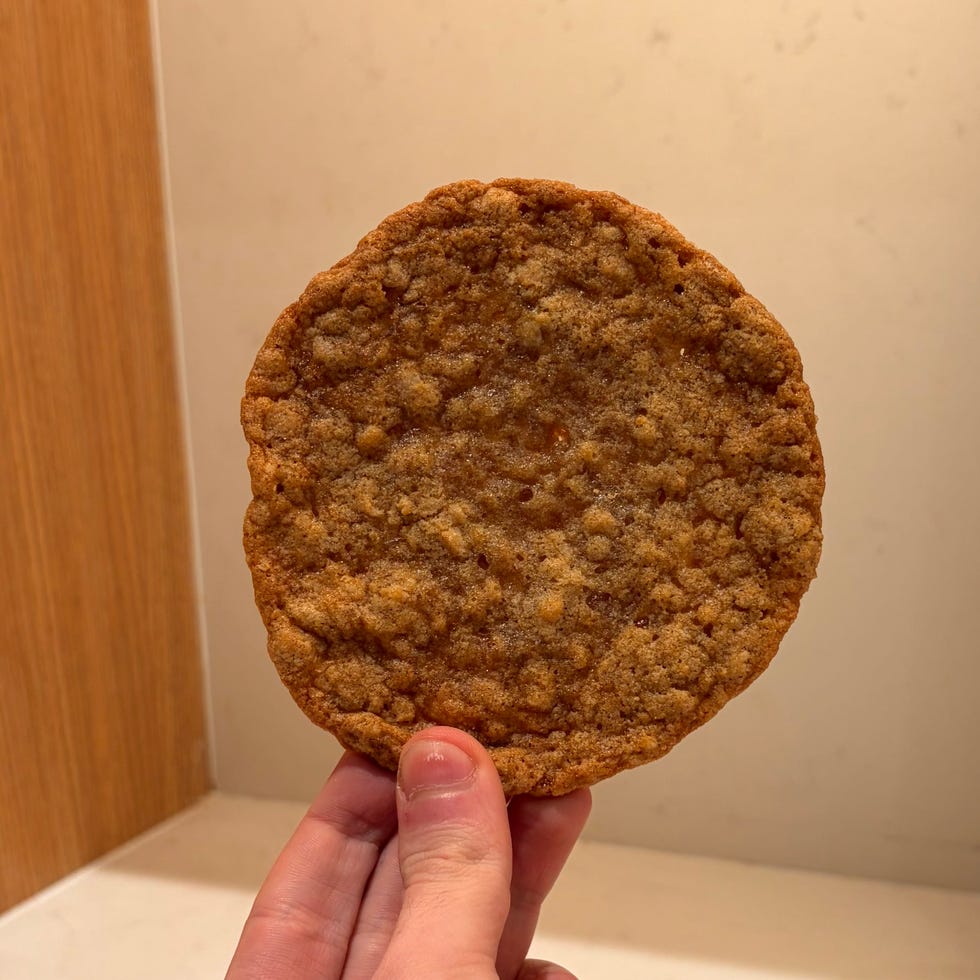 a hand holding a large cookie against a countertop