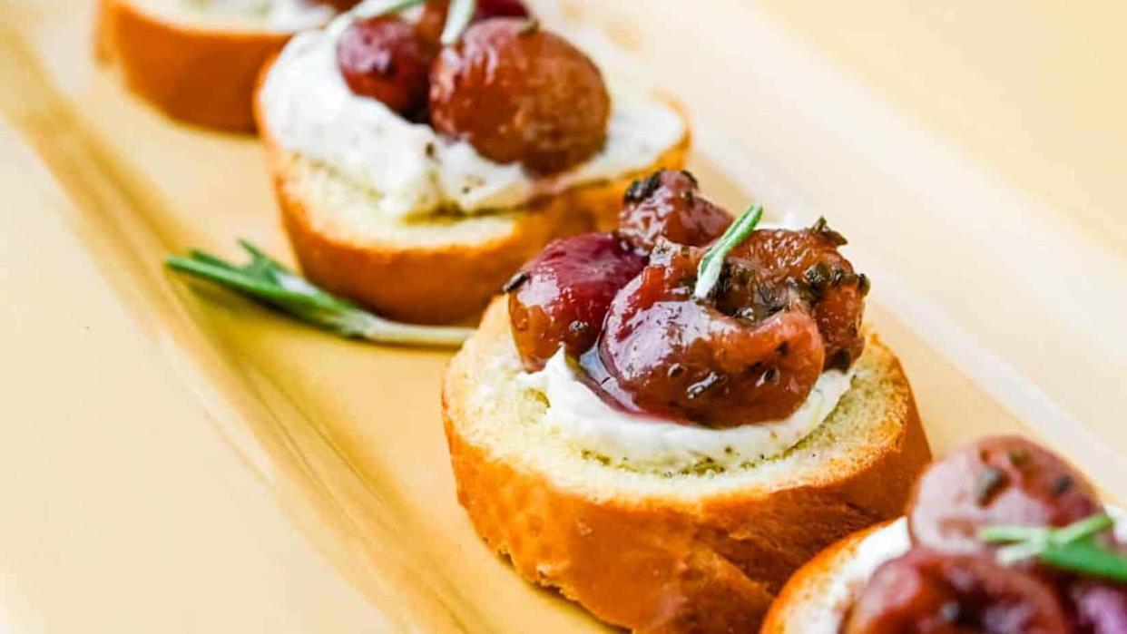 A close up shot of a few pieces of Roasted Grape Goat Cheese Crostini.