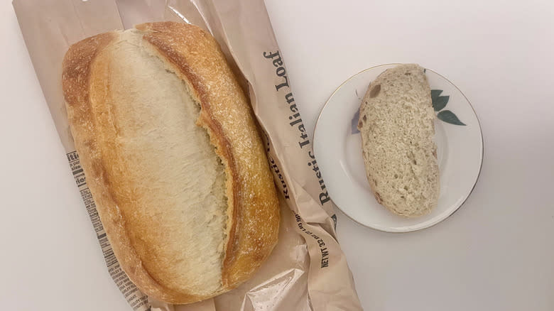 Top view of Bakery rustic Italian bread loaf with one slice on a plate next to it