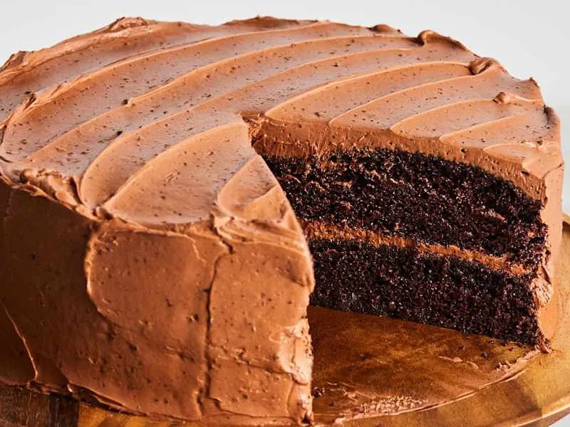 Ina Garten's "Beatty's Chocolate Cake" on a pedestal cake stand, with a slice taken