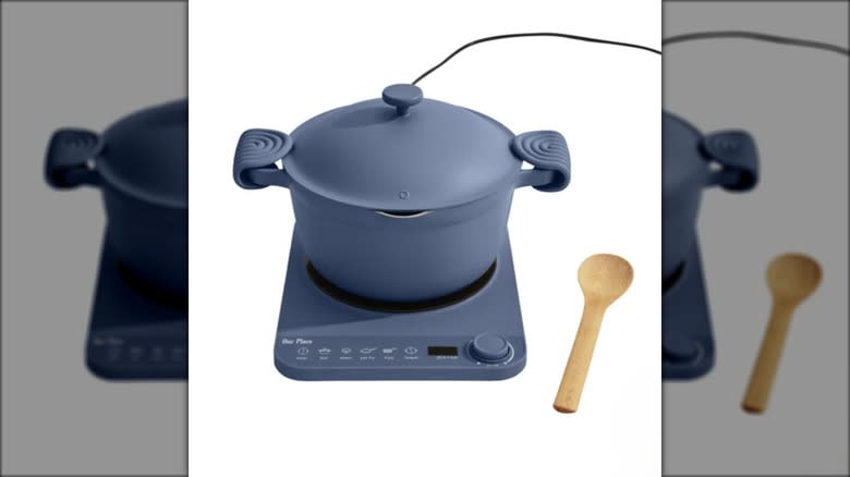 Gray-blue hot pot with induction cooker, wooden spoon on the side, against a white background.