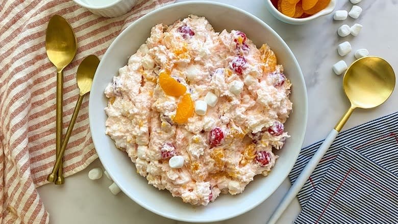 Ambrosia salad in white bowl, topped with mandarin slices and mini marshmallows