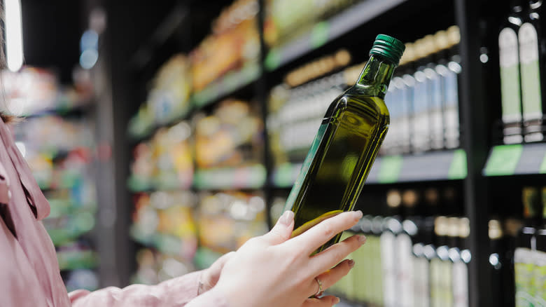 woman choosing olive oil at a grocery store