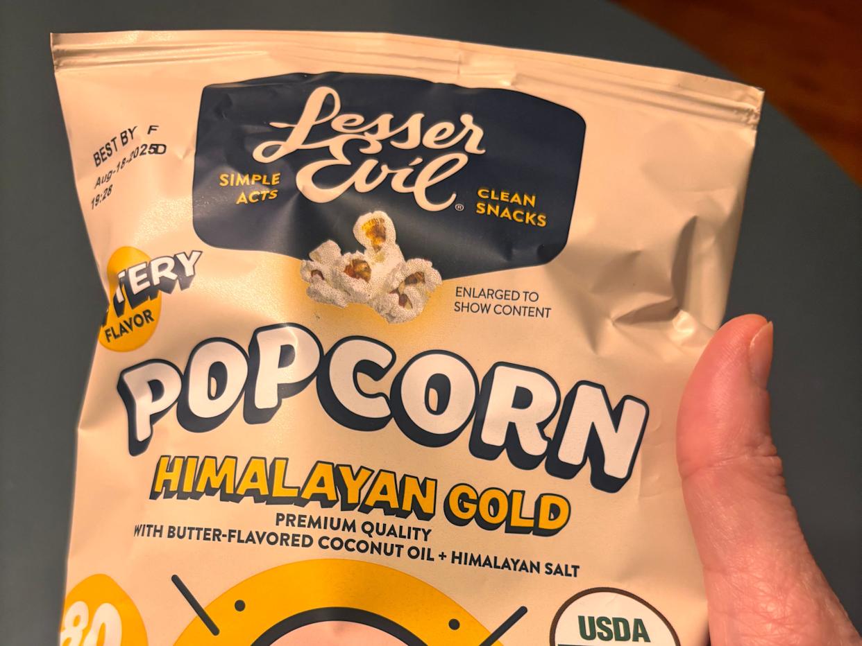 hand holding up bag of lesser evil popcorn