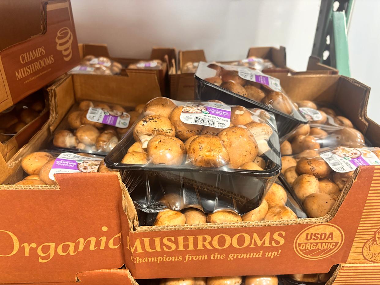 Plastic-wrapped packages of organic mushrooms in box at Costco