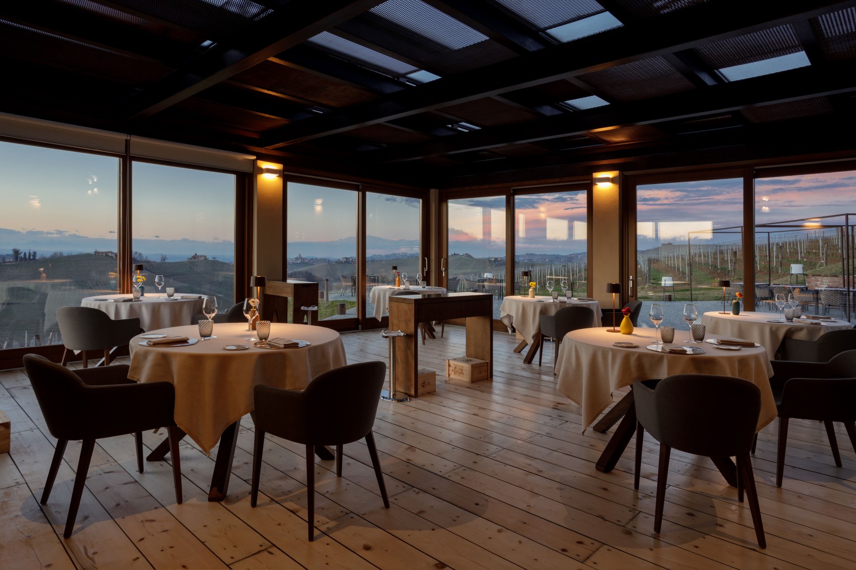 Ristorante Borgo Sant’Anna blends modern Piedmontese cuisine with stunning vineyard views through its glass-walled dining room in Langhe’s UNESCO region. © Borgo Sant'Anna  