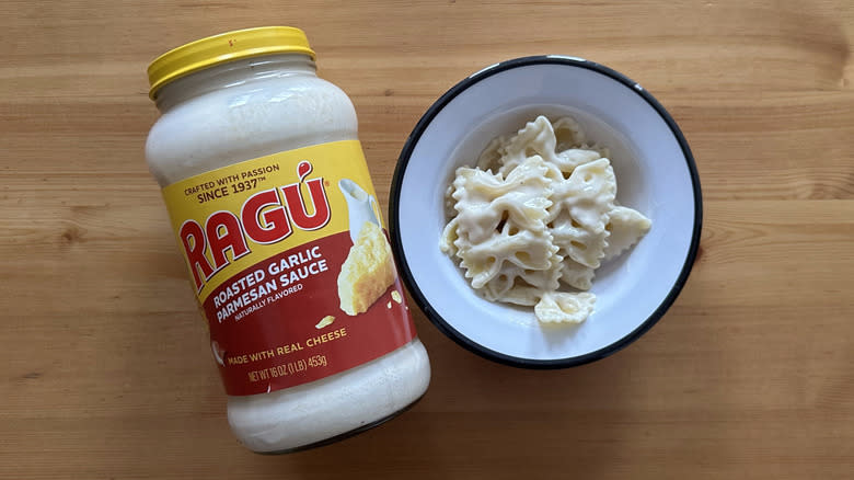 Jar of Ragú Roasted Garlic Parmesan Sauce next to bow tie pasta in sauce