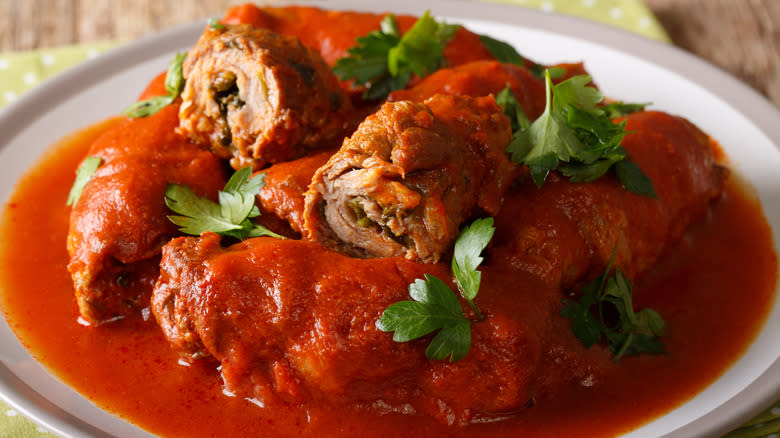 A plate of beef braciole smothered in tomato sauce