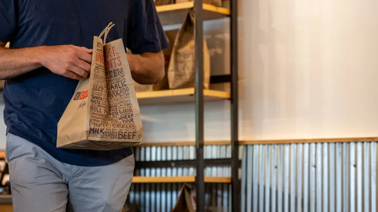 person leaving Chipotle with bag of food