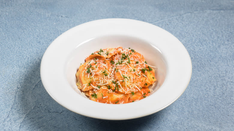 ravioli in tomato cream sauce in a white bowl