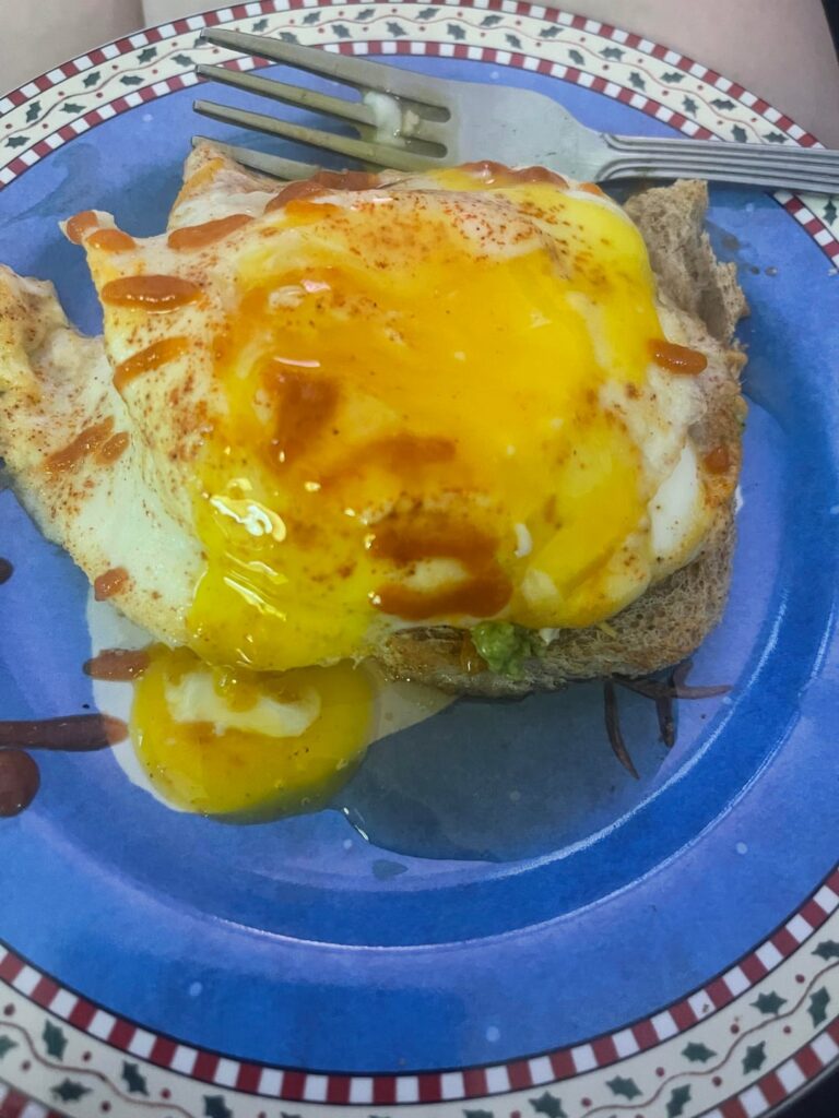 Cheesy toast with avacado, 2 sunny side up eggs, sriracha and syrup 🤤