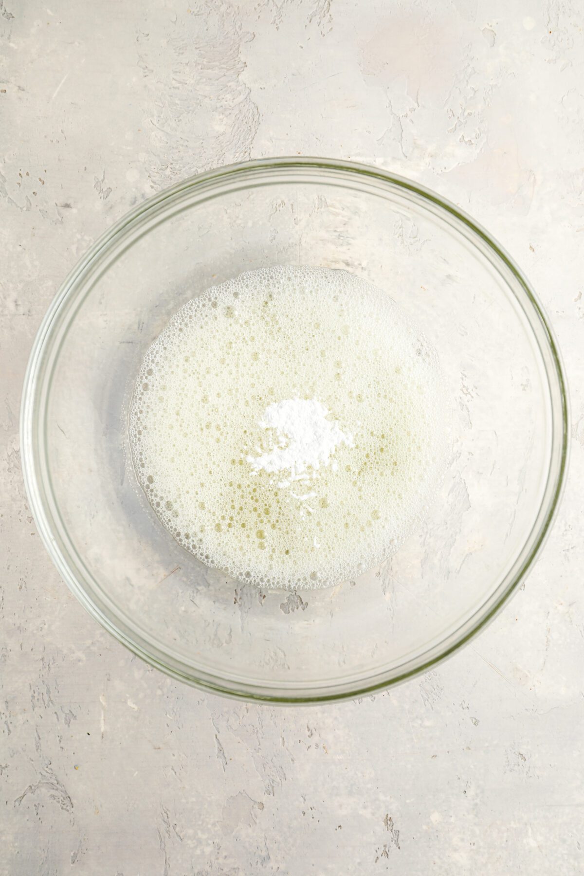 medium bowl with foamy egg whites and cream of tartar