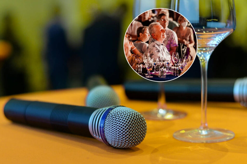 Microphones lie next to empty wine glasses on a table | Laughing audience at “An Idiot’s Guide to Wine”