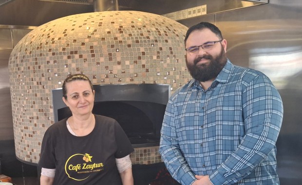 Hilana Yousef and Nick Kinton, who share management duties at the newly opened Cafe Zaytun in Elgin, stand in front of the brick oven imported from Lebanon that's used for flatbreads. (Mike Danahey/The Courier-News)