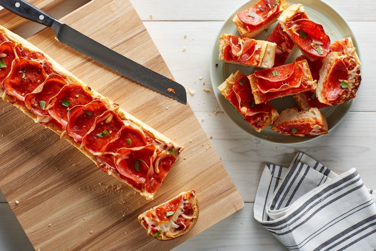 Image of french bread with mozzarella and pepperoni on a cutting board and stacked on a plate next to it.