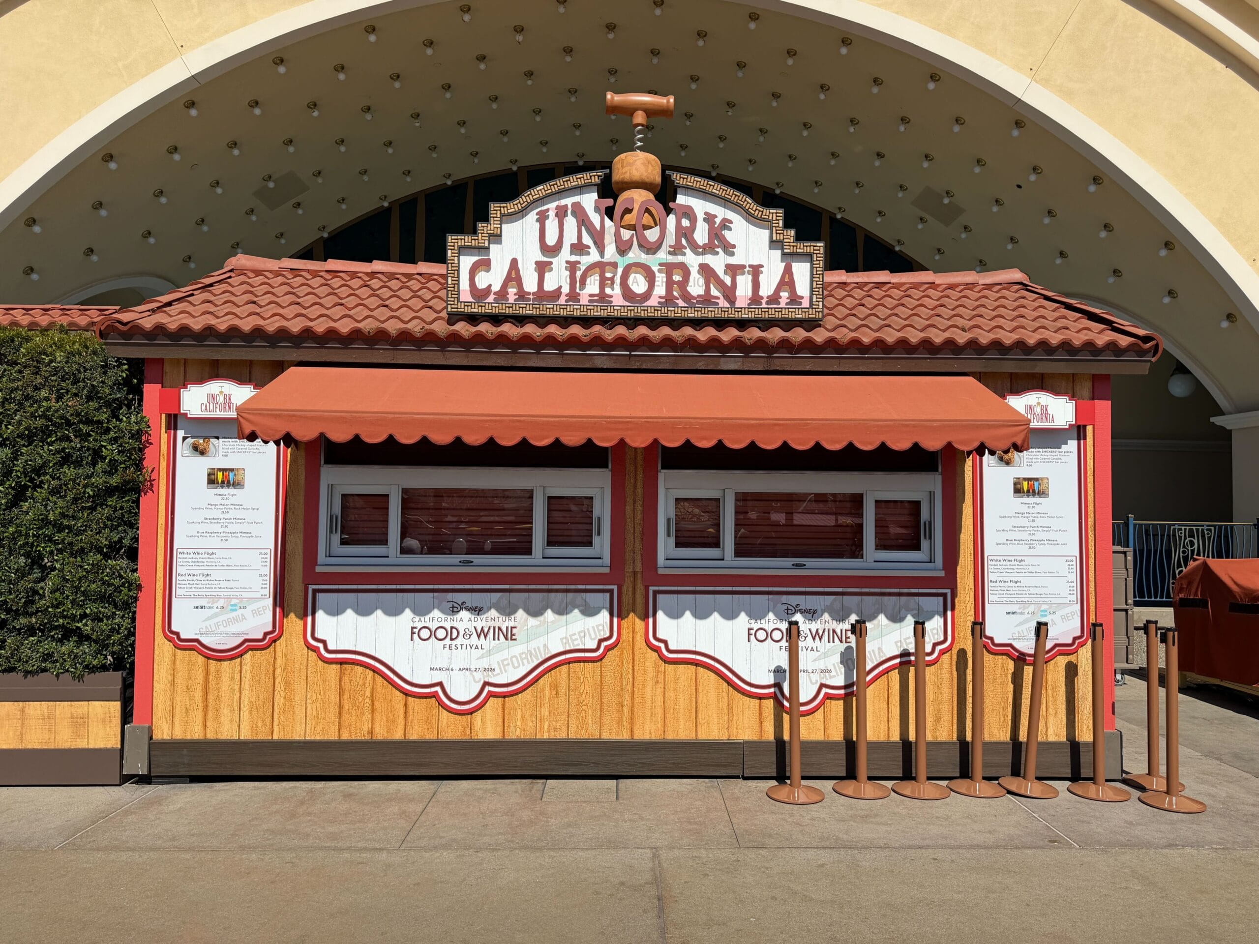 The booth Uncork California can be found near The Little Mermaid - Ariel's Undersea Adventure. The marquee has a wine cork with a corkscrew in it. this booth has two ordering windows.