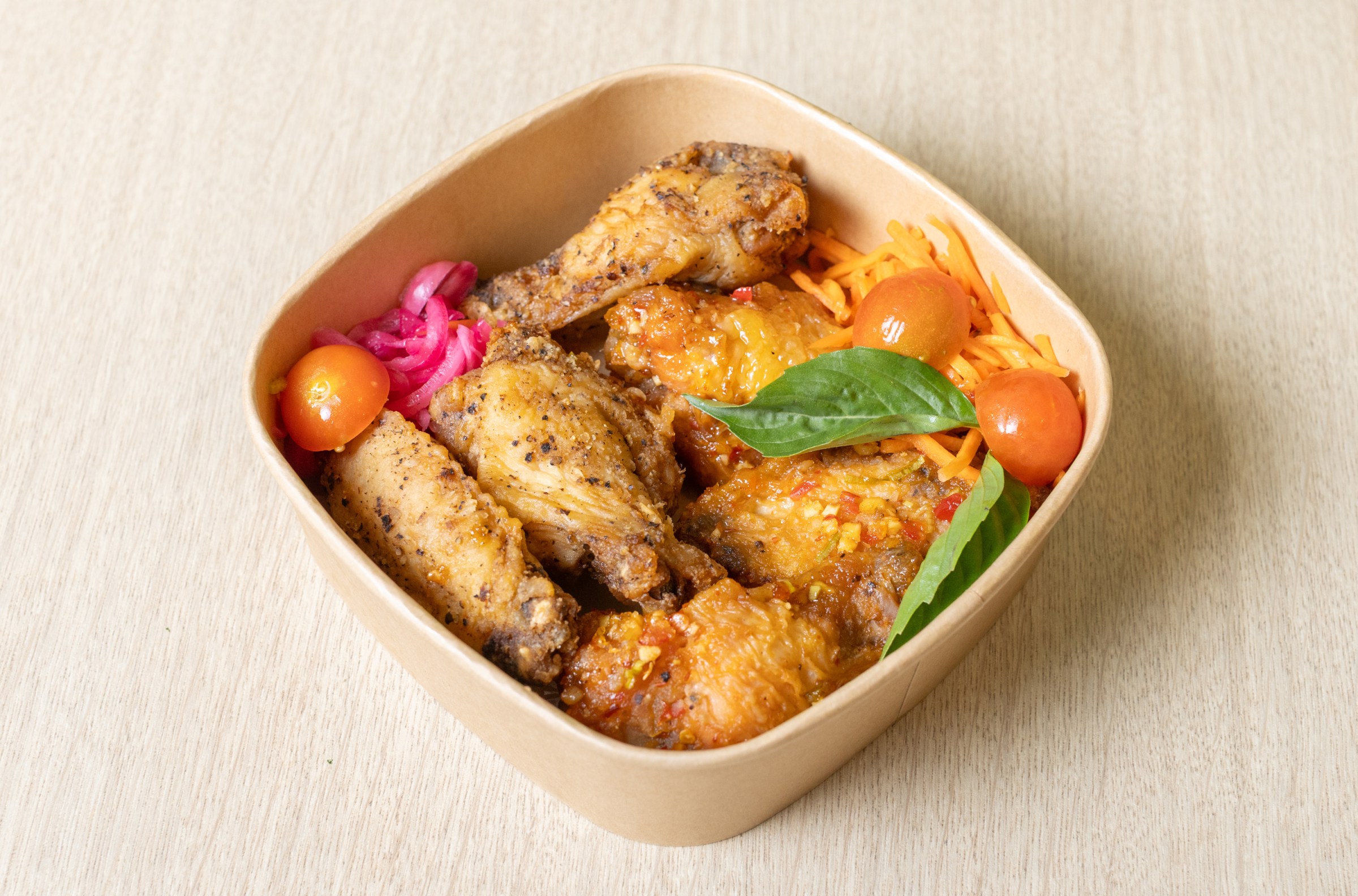 Chicken in a bowl with tomatoes carrots and pickled onions.