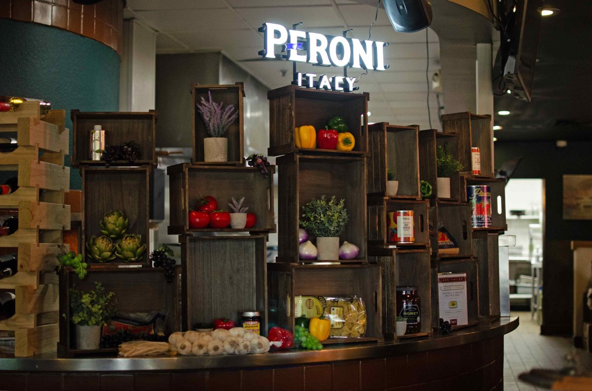 A wall of produce bins with various cans, plastic produce and other ingredients sits in front of the kitchen at Kevin's Italian Bistro.