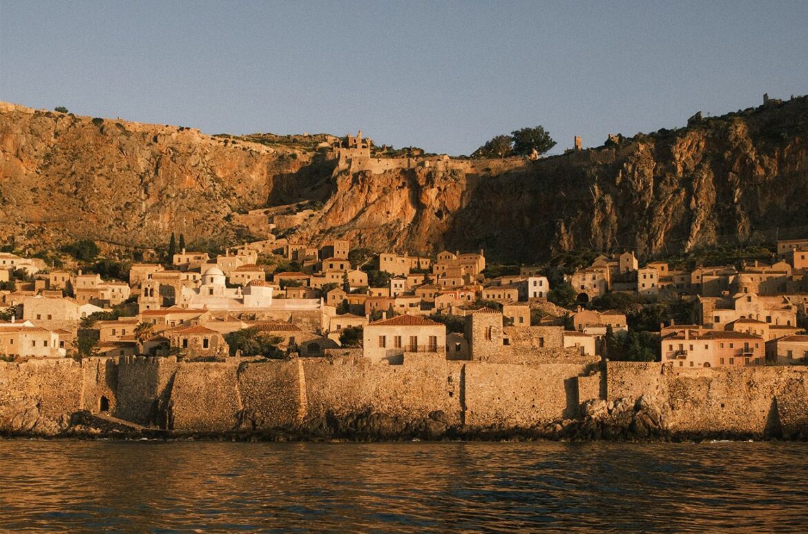 Small stone houses on the coast at sunset, with cliffs in the background