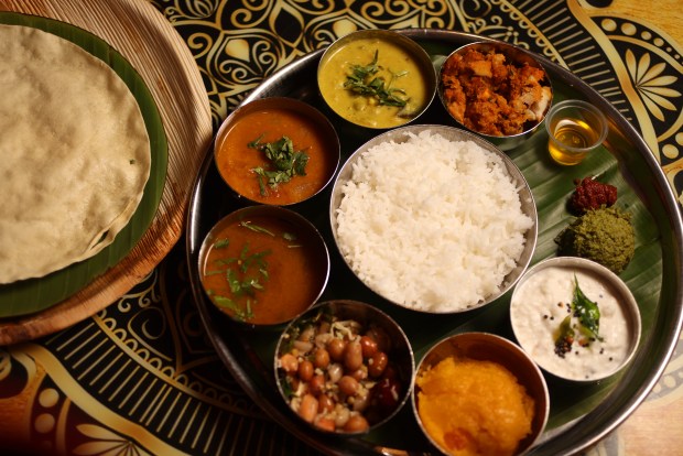 Mylapore's lunchtime "thali," as seen in San Jose, is served on a large, round platter filled with smaller bowls containing dishes like lentils, seasonal vegetables and rice for a full, balanced meal. On the side is fried urad lentil papad. (Aric Crabb/Bay Area News Group)