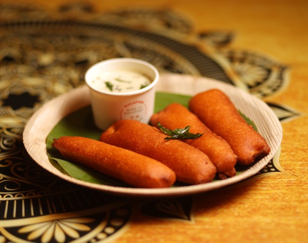 Vazhakkai Bajji, served at San Jose's Mylapore, is made by green plantain slivers folded into spicy chickpea batter and deep-fried a crisp orange-brown. It's then presented on a banana leaf with a coconut dipping chutney on the side. (Aric Crabb/Bay Area News Group)