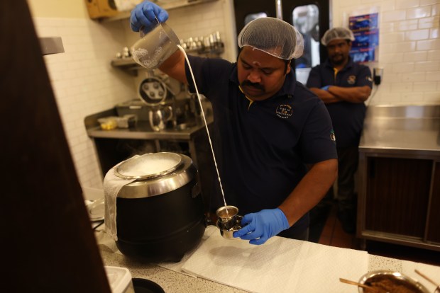 Indian filter coffee is prepared by pouring a stream of hot, foaming milk into a stainless steel tumbler sitting inside a steel davara at Mylapore restaurant in San Jose. (Aric Crabb/Bay Area News Group)