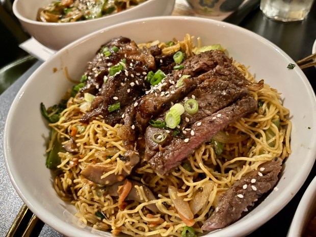 Thinly sliced ribeye atop a tangle of noodles and vegetables
