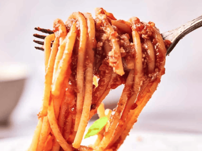 Spaghetti marinara in a bowl with fresh basil on top..