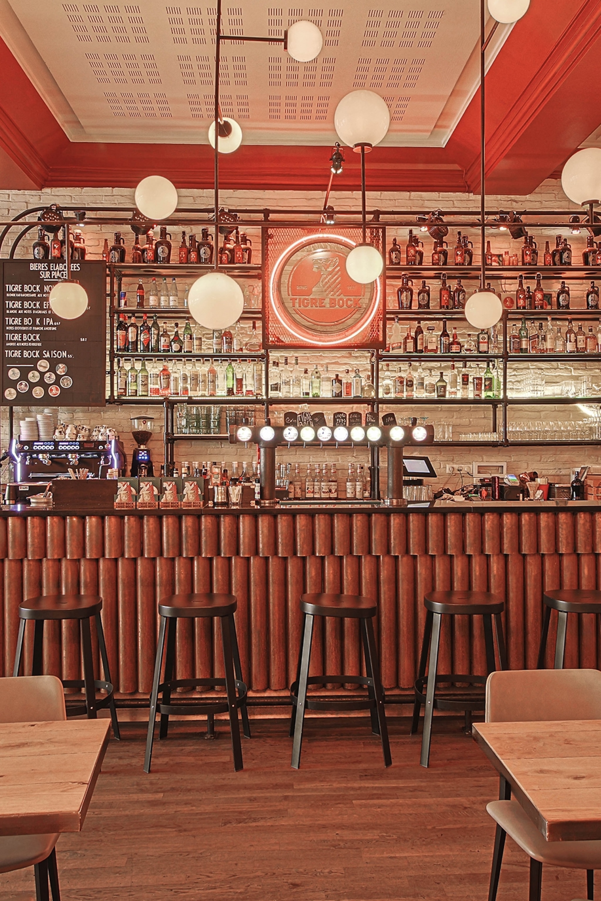 A warm bar with globe lights hung above and liquor lined up on the wall behind.