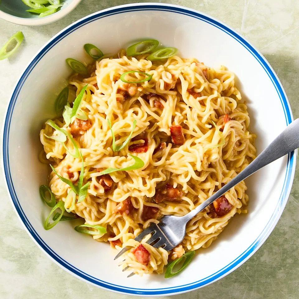ramen mixed with eggs and bacon topped with chives