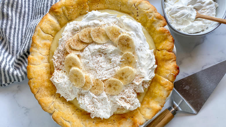 Banana cream pie topped with whipped cream and sliced banana