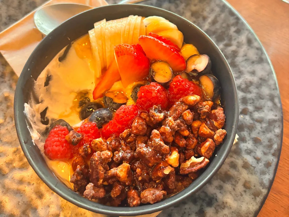 Bowl of yogurt, fruit, and granola with honey.