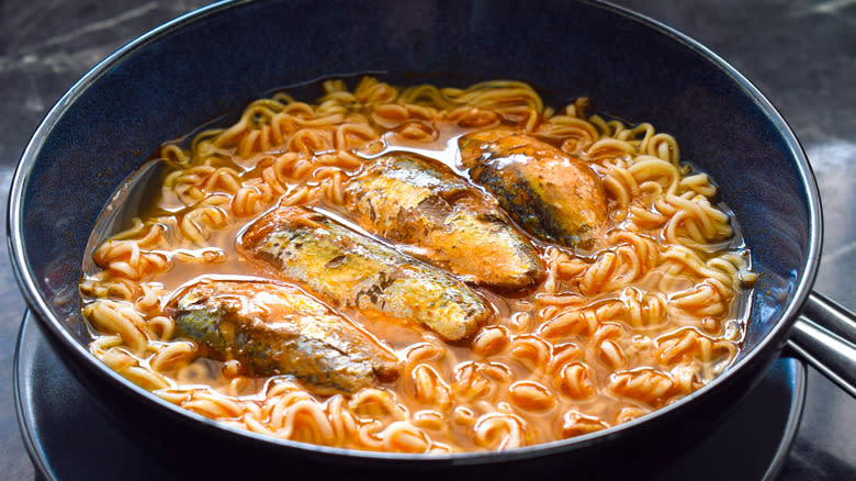 A blue bowl of tomato-based ramen with seafood in it