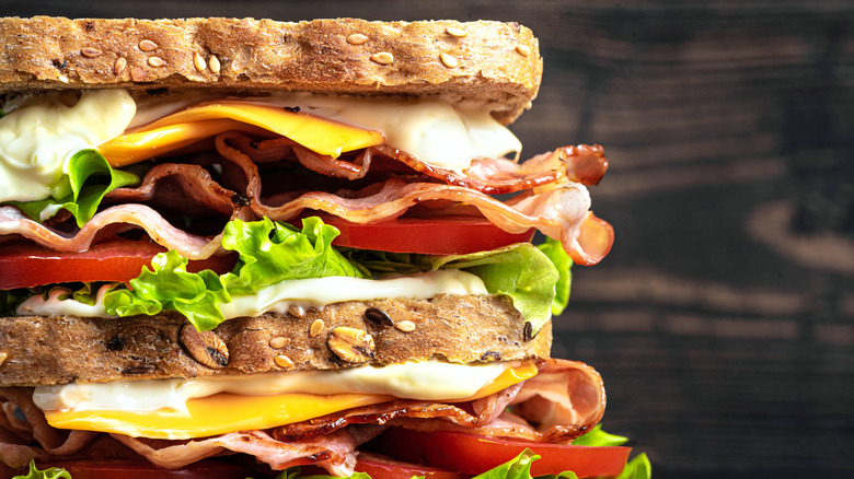 A double BLT sandwich with cheese and creamy mayo on whole grain bread