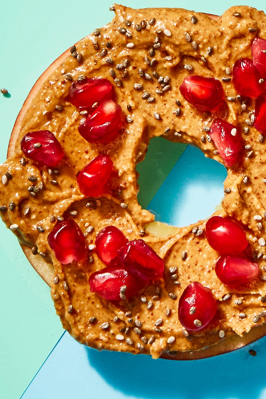 apple slice with almond butter and pomegranate seeds on top