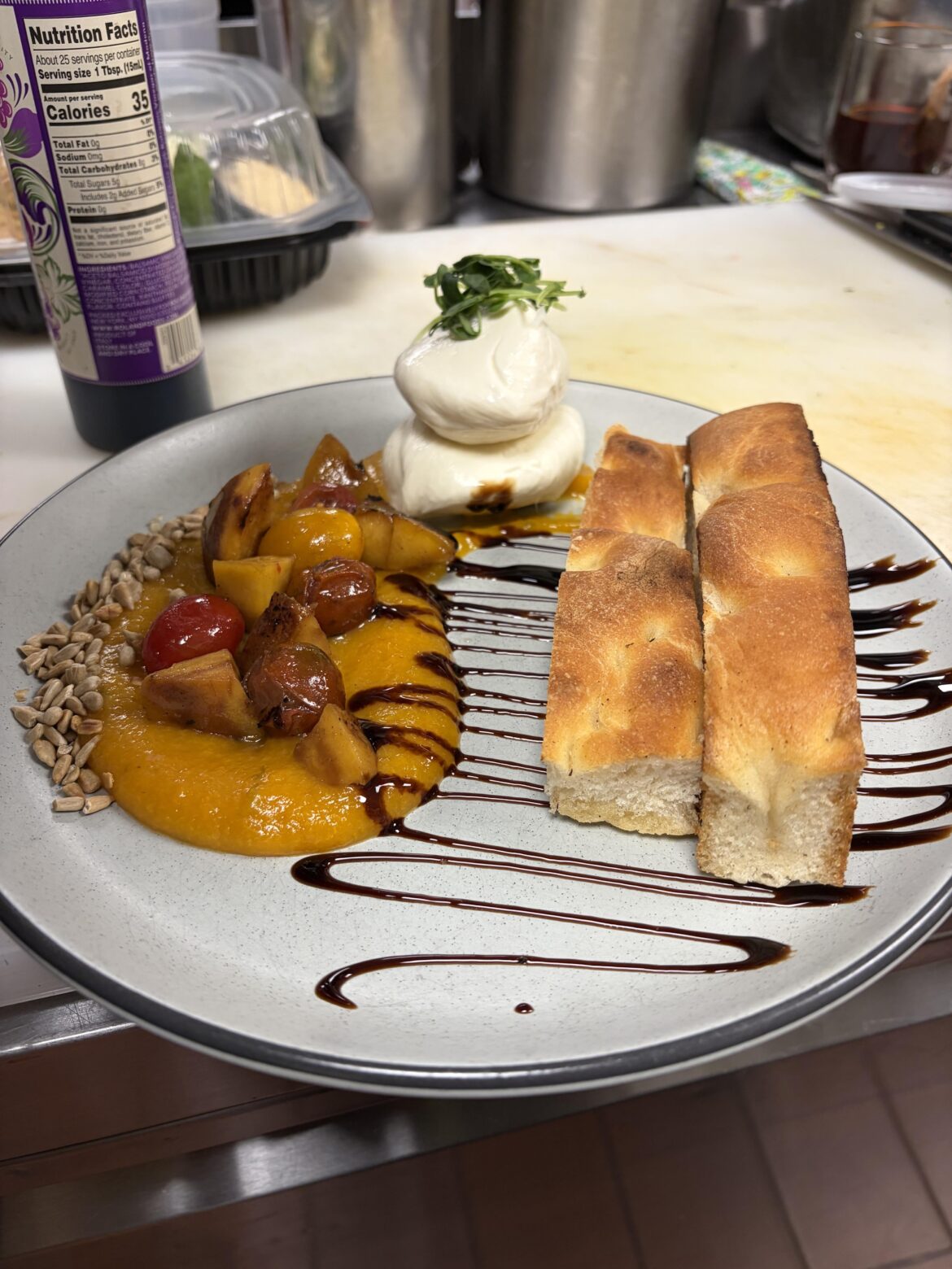 Burratta with peach coolis, roasted peaches and cherry tomatoes, sun flour seeds, fig glaze and foccacia
