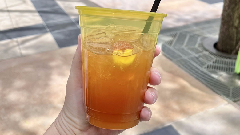 Hand holding a cup of Bourbon Peach Tea Lemonade