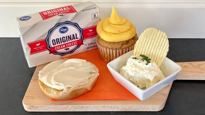 Kroger brand cream cheese on a wooden cutting board with bagel, cupcake and chip dip