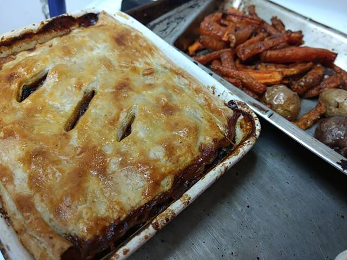 A pastry-covered chicken pot pie fresh out of the oven in a square white casserole dish.