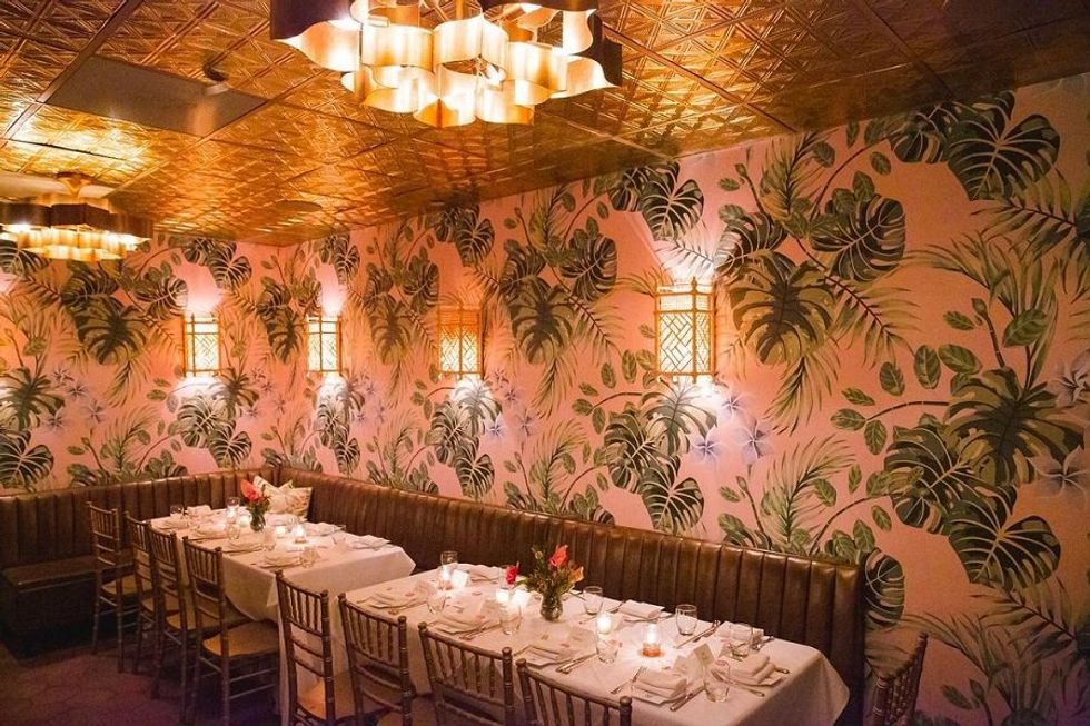 Cozy restaurant with floral wallpaper, elegant lighting, and a set dining table.