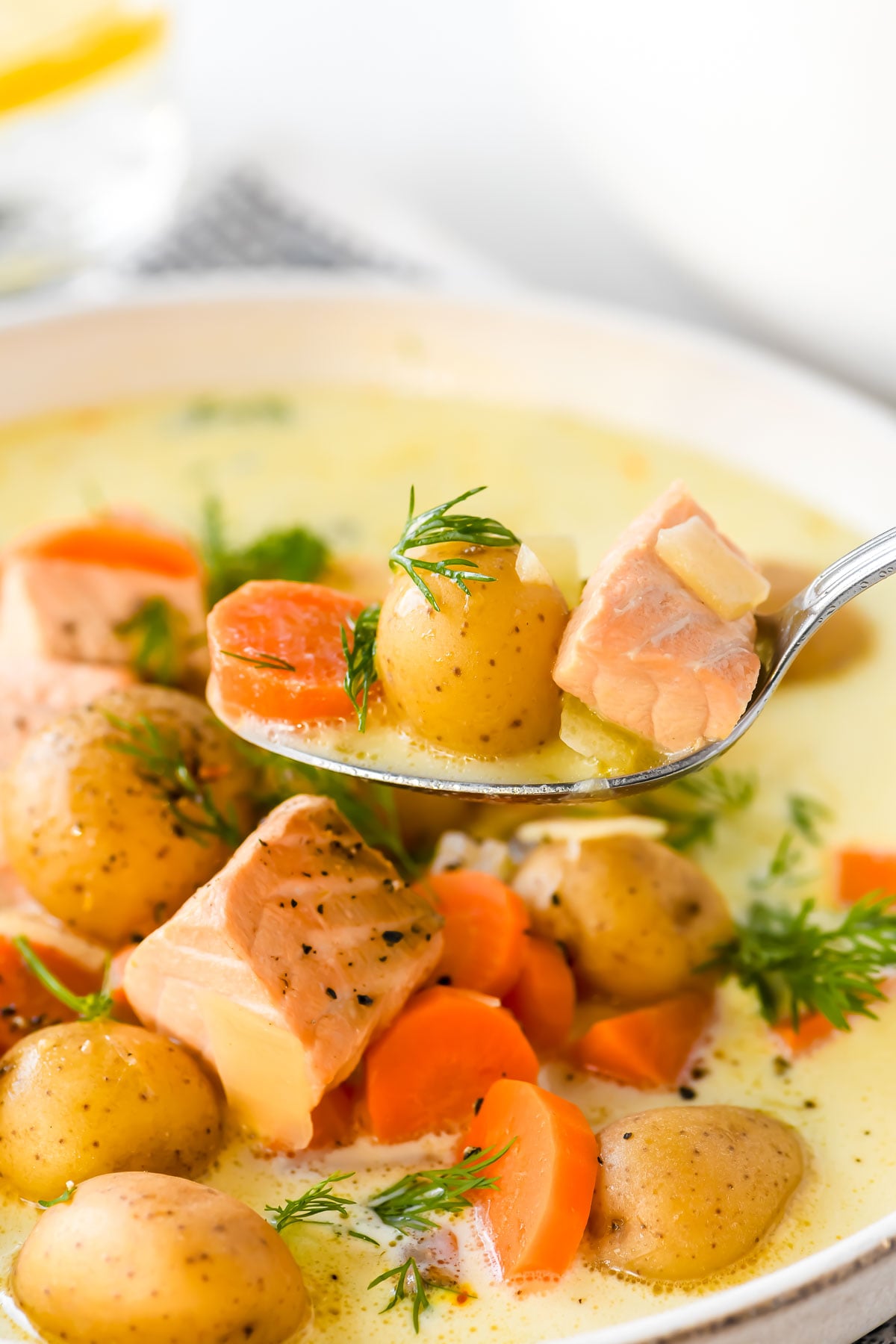 Taking a spoonful of creamy lemon salmon soup.