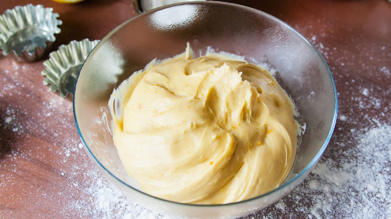 Brioche dough in clear bowl on floured surface