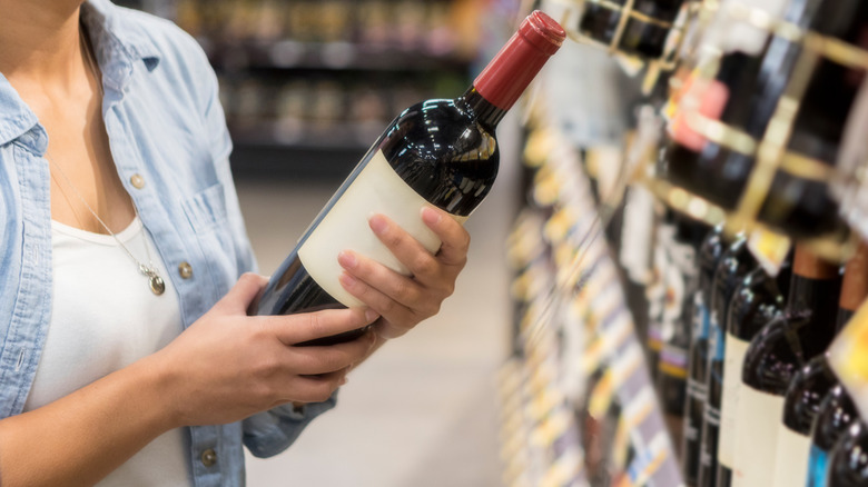 Customer holding bottle of red wine in store
