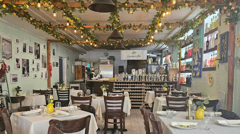 Daytime interior view of Limoncello Italian restaurant in Miami, Florida with lemon garlands draped on the ceiling, black and white photos on the walls, and lemon decor on white tablecloths