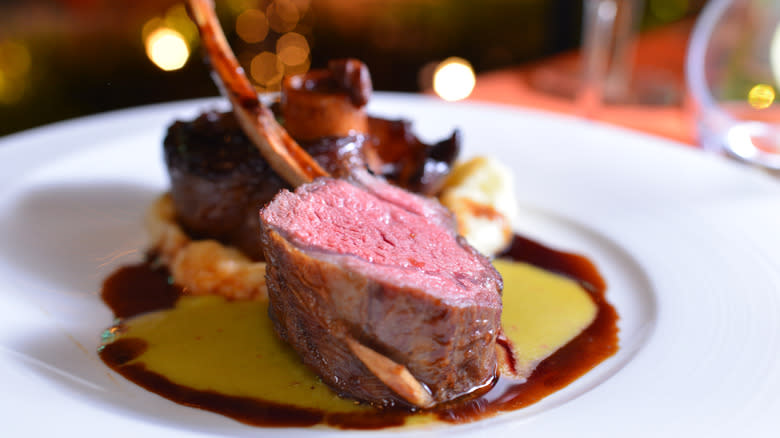 Gourmet tomahawk steak on white plate on top of sauce