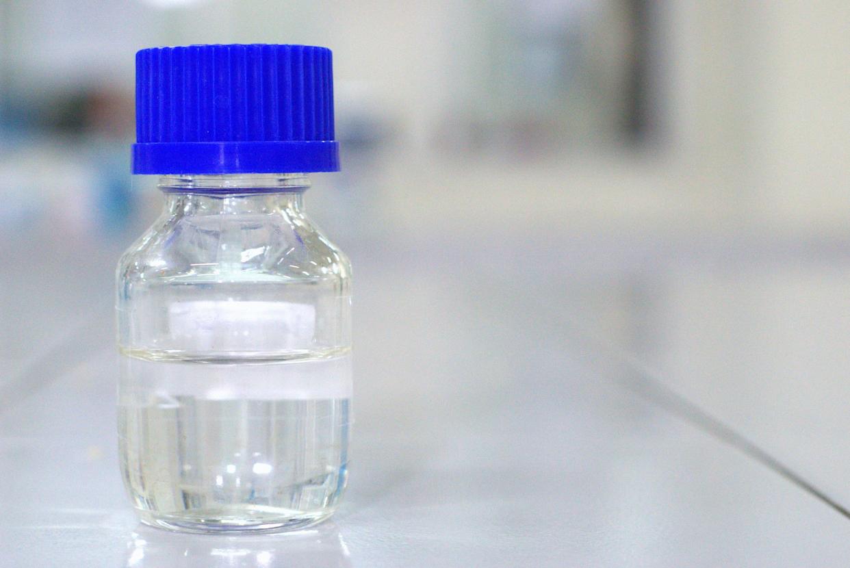 Transparent laboratory bottle glass with blue cap on a laboratory bench with copy space