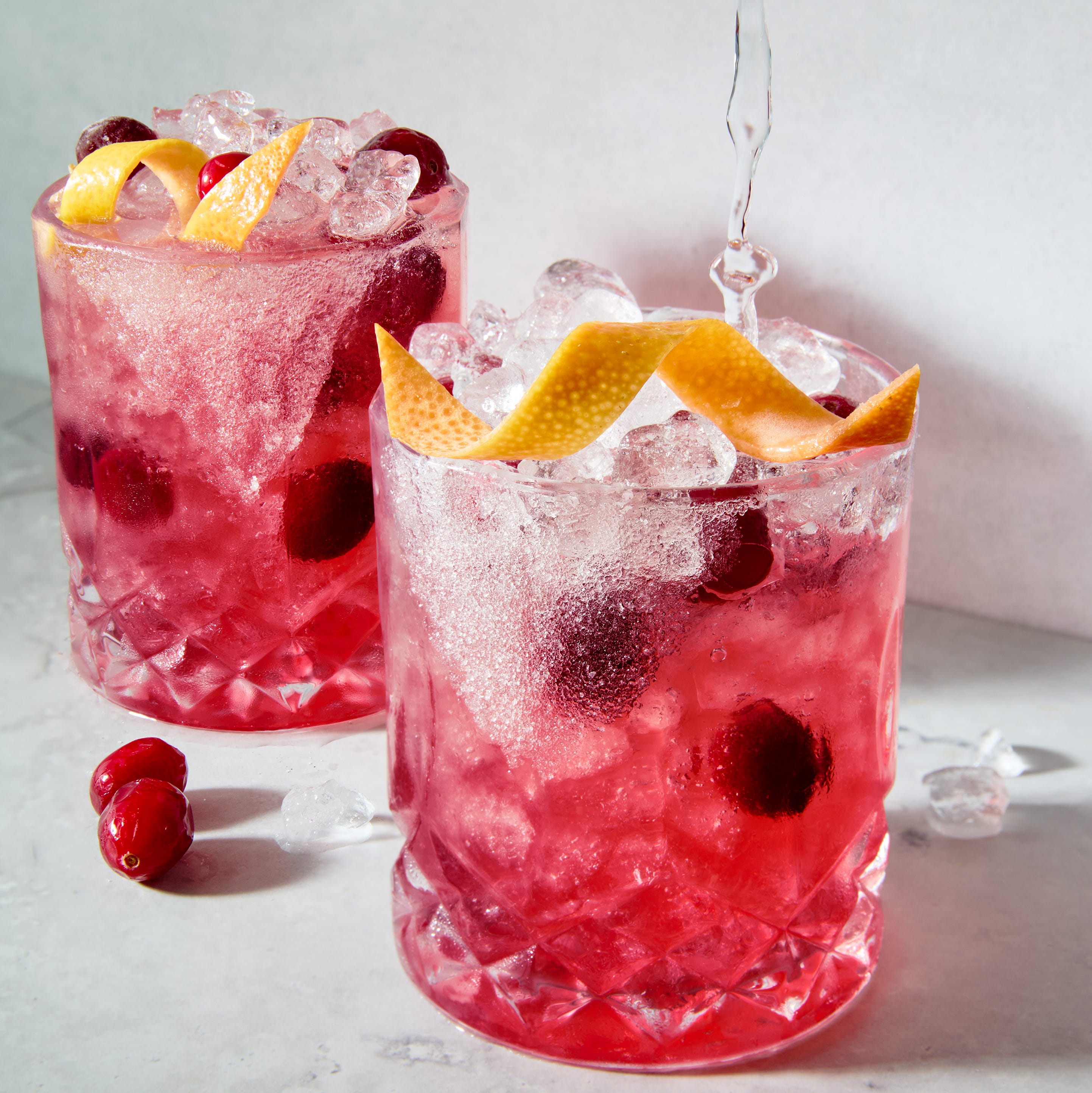 a short glass with a sugar rim, filled with a tequila grapefruit and cranberry cocktail, garnished with a grapefruit twist and fresh cranberries