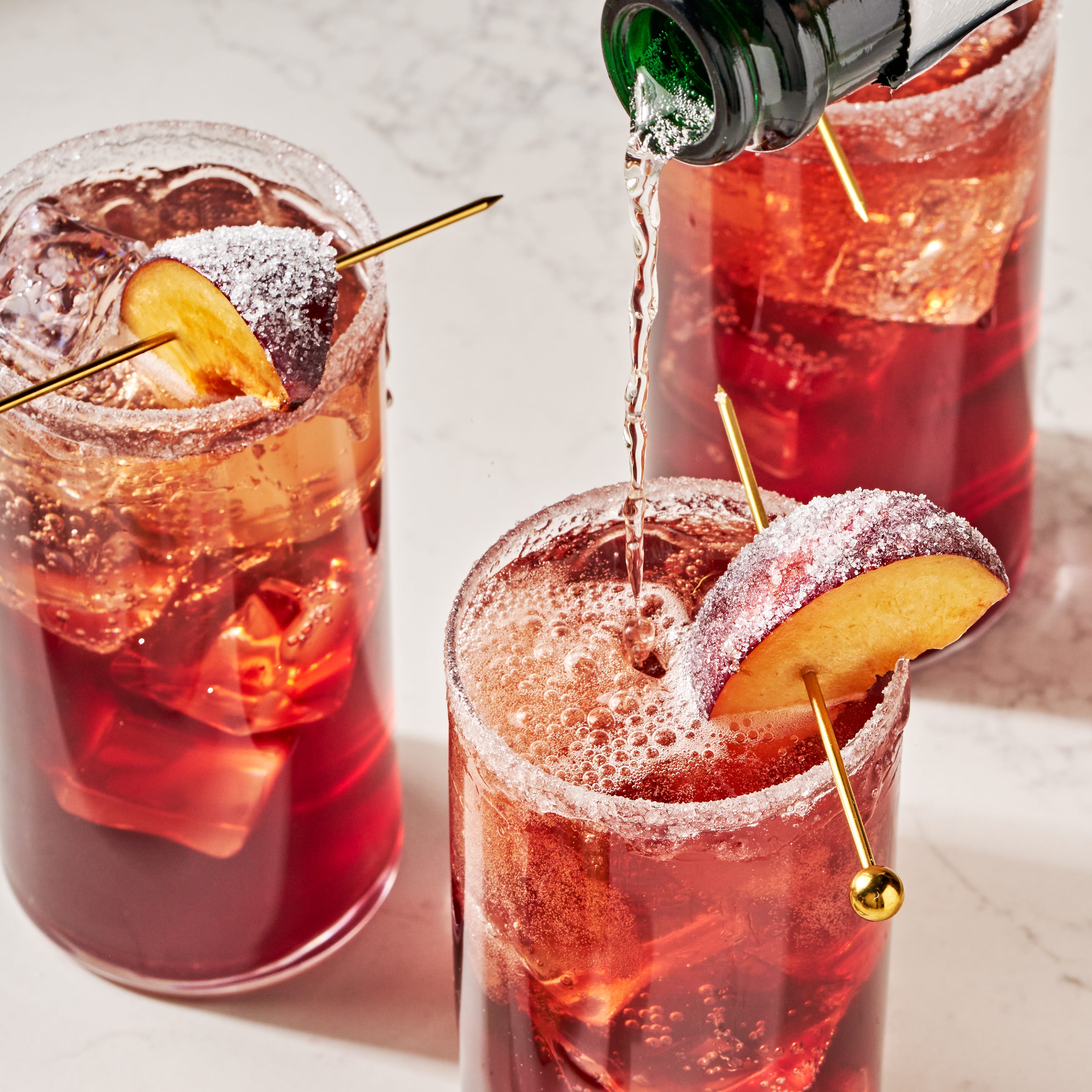 a refreshing holiday cocktail with plum wine, prosecco, maraschino cherry syrup, lemon, and bitters, garnished with a sugared plum